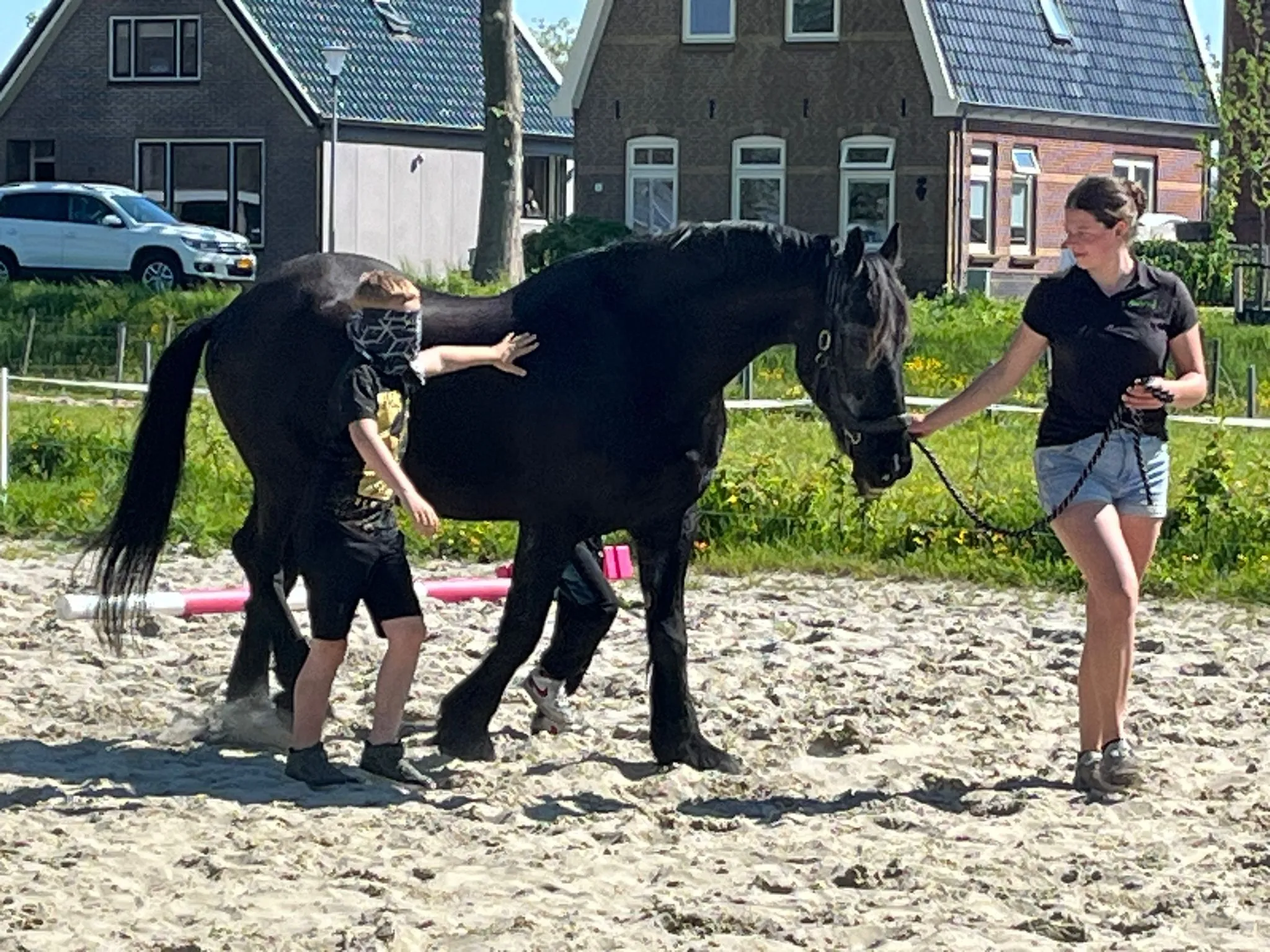 Begeleider en kind werken samen met een paard in de manege bij ’t Bonte erf